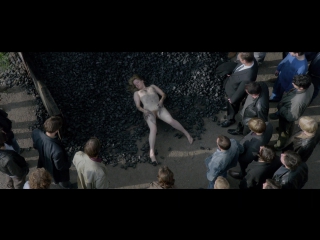 #35 a naked girl lies on black stones surrounded by men